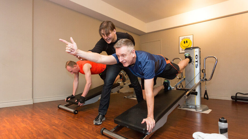 How to achieve a fit body with personal training in Yaletown? Troy guiding his client in the proper form